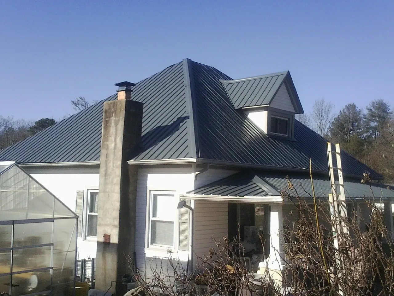 Dark blue standing seam metal roof on a white farmhouse with dormer — Slate & Tile Roof Repair by Roofing Brothers in Westpoint