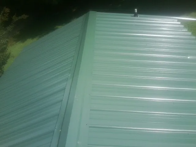 New green metal panels meeting at the ridge of a roof — Flat Roof Repair work by our crew in Westpoint
