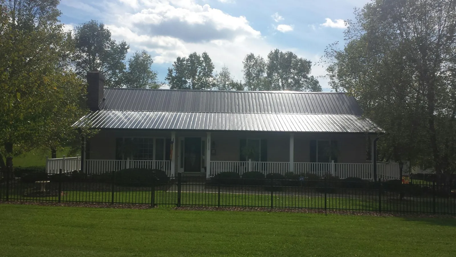 Gray metal roof on a brick ranch with a full width front porch — Gutter Guard Installation work by our crew in Westpoint