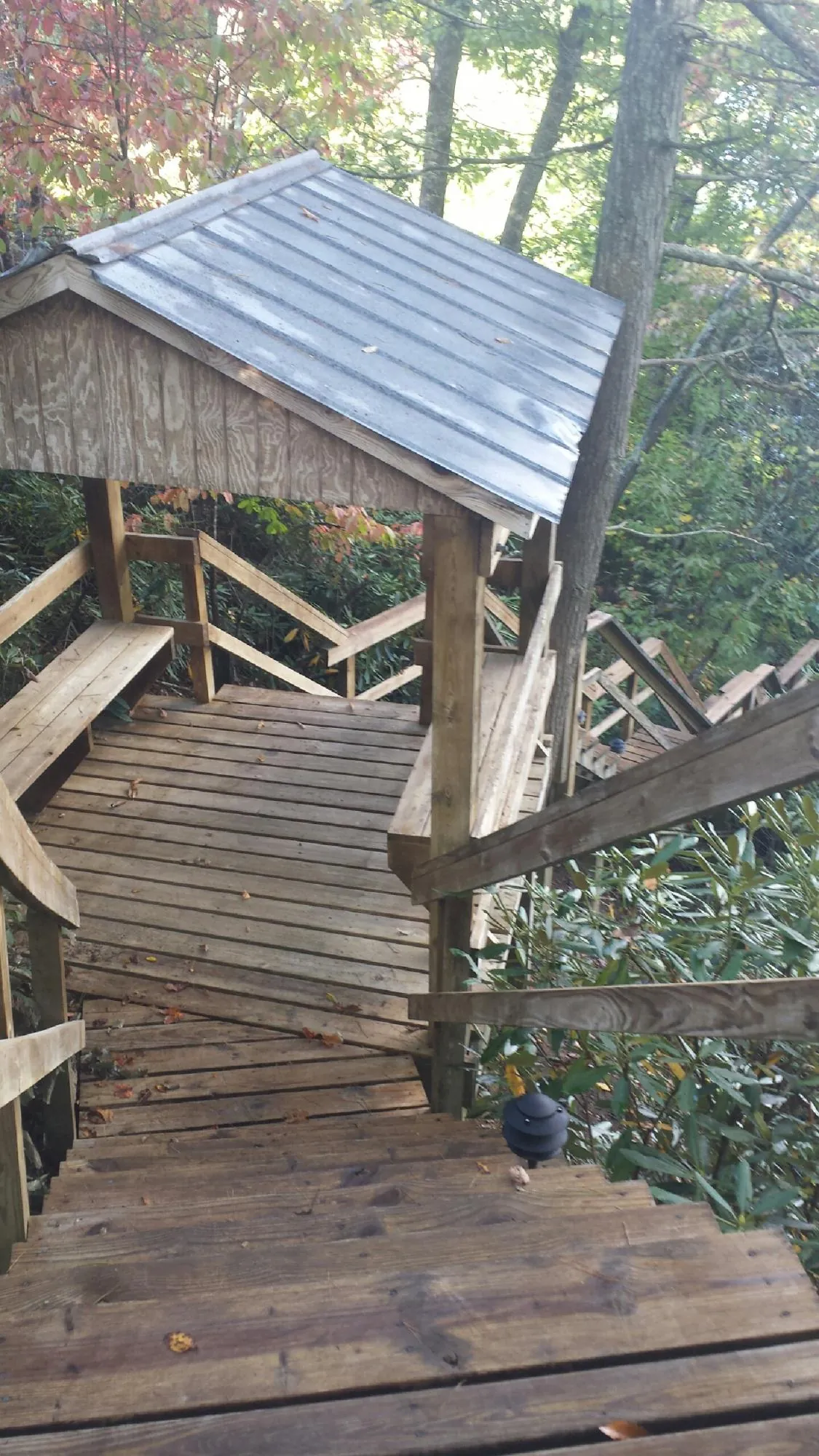Metal roofed shelter over wooden steps on a wooded walkway — Skylight Repair & Installation work by our crew in Westpoint